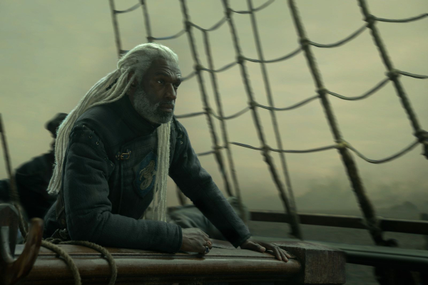 Lord Corlys Velaryon  stands on his ship in a still from season three of House of the Dragon.